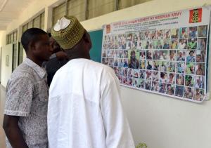 Peolpe look at a poster in Maiduguri, displaying one …