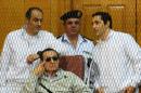 Egyptian toppled president Hosni Mubarak and his two sons Alaa (R) and Gamal stand behind bars during their trial at the Police Academy on September 14, 2013 in Cairo