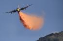 An aircraft drops fire retardant on the Colby Fire on Friday, Jan. 17, 2014, near Azusa, Calif. Firefighters were chasing flare-ups Friday morning in the damaging wildfire that was largely tamed but kept thousands of people from their homes in the foothill suburbs northeast of Los Angeles.(AP Photo/Jae C. Hong)