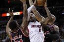 Miami Heat's LeBron James struggles to shoot against Chicago Bulls' Jimmy Butler and Carlos Boozer during their NBA basketball game in Miami