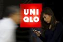 File photo of a woman holding her mobile phone standing next to a logo of Fast Retailing's Uniqlo outside its store in Tokyo