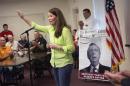 FILE - This July 30, 2014, file photo shows U.S. Senate candidate and Kentucky Secretary of State Alison Lundergan Grimes (D-KY), as she speaks to supporters in Hawesville, Ky., as a poster of her rival Senate Minority Leader Mitch McConnell of Ky., serves as a backdrop. The annual picnic at Fancy Farm always serves up a main dish of politics along with a side of delicious barbecue. And on Aug. 2, 2014, voters will get a rare glimpse of Kentucky's U.S. Senate candidates standing side by side as they face armies of hecklers trying to spook them off their talking points. McConnell and his Democratic challenger, Grimes, will share the same stage for only the second time.(AP Photo/David Stephenson, File)