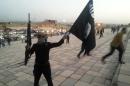 A fighter of the ISIL holds a flag and a weapon on a street in Mosul