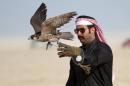 Qatari man releases his falcon during a falcon contest at Qatar International Falcons and Hunting Festival at Sealine desert