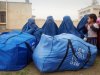 In this Thursday, Nov. 24, 2011, Afghan women clad in burqas sit near their packed bags of humanitarian aid donated by International Organization for Migration (IOM) for drought-hit families in Mazar-e-Sharif, Balkh province, north of Kabul, Afghanistan. The United Nations appealed for $142 million on Oct. 1 to help those hit by the drought in 14 northern provinces where up to 80 percent of non-irrigated fields yielded little to no crops. So far, about $49 million has been pledged by aid groups, the U.S. and European nations. (AP Photo/Mustafa Najafizada)