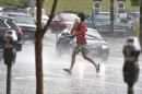 A man runs across the street carrying his dog, as a hail storm falls over downtown Denver, Thursday May 22, 2014. More spring thunderstorms began rolling into the Front Range and eastern Colorado on Thursday, a day after six tornadoes touched down east of Denver. Heavy hail was reported in Red Feather Lakes northwest of Fort Collins, and more hail is falling in Denver. (AP Photo/Brennan Linsley)