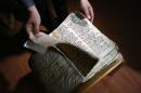 In this Thursday, April 2, 2015 photo, Raad Abdul-Ahed, 45, who was displaced from his home by the advance of Islamic State militants, shows a centuries-old handwritten biblical manuscript in the old Syriac language in a small apartment room in the Kurdish city of Dahuk, northern Iraq. As Islamic State group militants advanced toward the monastery in northern Iraq last year, the monks were determined to protect a fragile, vital piece of their heritage: They sent their library of centuries-old handwritten manuscripts to safety. Now the documents are hidden in an apartment in Iraq's Kurdish areas. (AP Photo/Bram Janssen)