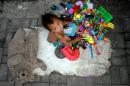 A homeless boy plays with toys collected by his parents who pick through trash to find used plastic soda bottles to sell in Manila on January 13, 2016