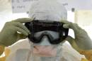 A health worker puts on protective gear in Liberia, where Ebola has spread across the entire country