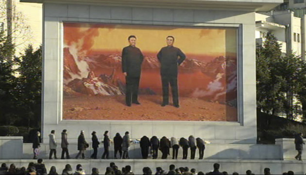 In this image made from Associated Press Television News, North Koreans gather to mourn the death of North Korean leader Kim Jong Il in front of a mural depicting Kim Jong Il and his father Kim Sung I