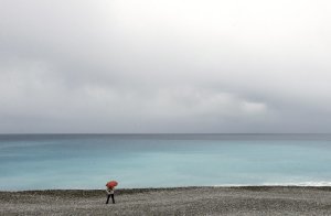 A person walks on the beach along the Mediterranean …
