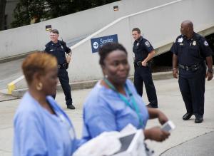 Hospital workers pass police officers guarding an entrance&nbsp;&hellip;