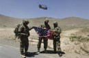 NATO soldiers stand with U.S. flag as a Chinook helicopter takes off after a security handover ceremony at a military academy outside Kabul