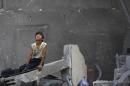 A Palestinian boy sits on the rubble of a destroyed building following an Israeli air strike in the center of Gaza City on July 22, 2014
