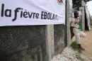 A young man stands near a banner reading ''Ebola fever!!'' ahead of a football tournament near the Koumassi sports center in Abidjan on August 10, 2014