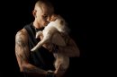 In this April 24, 2012 image, former Marine Christian Ellis, 29, holds his dog as he stands for a portrait in his apartment in Denver. Ellis has a swash of red ink among his tattoos for every friend and Marine killed in battle or by suicide. The former Marine machine gunner, who has attempted suicide four times, is putting his pain on stage in the first opera believed written about the Iraq War. (AP Photo/Gregory Bull)