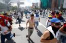 Protesters run after clashes with the police during a rally to demand a referendum to remove Venezuela's President Nicolas Maduro in Caracas