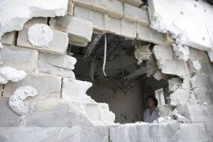 Woman is seen through hole in damaged residential building,&nbsp;&hellip;