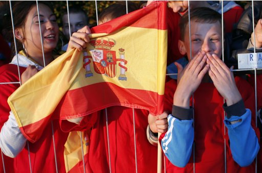 Local fans hold a Spain flag as the Spanish soccer team arrive at their training base in Gniewino