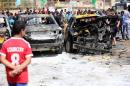 Iraqis inspect burnt out cars at the site of a car explosion on May 13, 2014 in Baghdad's northern Shiite-majority district of Sadr City