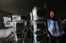 Afghan election worker stands next to ballot boxes at a counting centre in Kabul