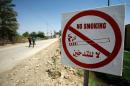 Iraqi youths run near a sign indicating that smoking is forbidden in the southern Iraqi village of Albu Nahedh, in the al-Saniya area in Iraq's southern al-Diwaniyah province, on June 15, 2015