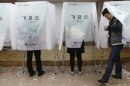 Young South Korean's cast their absentee ballot at a polling station in a Goshichon in Seoul