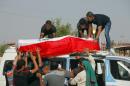 Family members of Ali Jamal, 23, who was killed in a bomb attack, load his flag-draped coffin onto a vehicle before burial in the Shiite holy city of Najaf, 100 miles (160 kilometers) south of Baghdad, Iraq, Monday, May 12, 2014. Bombings and shootings killed several people in areas south of the Iraqi capital on Monday, authorities said. (AP Photo/Jaber al-Helo)