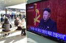 Travellers sit by a television screen showing North Korean leader Kim Jong-Un's New Year speech, at a railroad station in Seoul on January 1, 2015