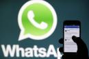 A Whatsapp App logo is seen behind a Samsung Galaxy S4 phone that is logged on to Facebook in the central Bosnian town of Zenica