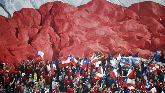 Fans cheer next to a giant flag of Chile, top, during a Copa America quarterfinal soccer match between Uruguay and Chile at the National Stadium in Santiago, Chile, Wednesday, June 24, 2015. (AP Photo/Silvia Izquierdo)
