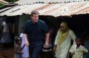 British Prime Minister David Cameron emerges from a hut housing Tamil conflict displaced residents at the Sabapathi Pillay Welfare Centre in Jaffna, on November 15, 2013
