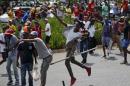 Students throw stones during a confrontation with security guards as they protest over planned increases in tuition fees outside the University of Johannesburg