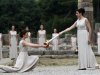 An actress as a high priestess, right, passes on the Olympic flame she has just lit using a concave mirror to concentrate the sun's rays, to a priestess holding a cauldron during the lighting of the flame ceremony held on Thursday May 10, 2012, in Ancient Olympia, Greece. The flame, lit in the birthplace of the Ancient Olympics, will travel to London, where the Summer Games will take place from July 27-Aug. 12. (AP Photo/Petros Giannakouris)