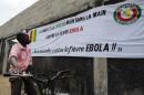 A boy looks at a banner reading 'Guinea and ECOWAS hand in hand against Ebola fever', 'All together against Ebola fever!' prior to a football tournament gathering youth from Guinea near in Abidjan on August 10, 2014