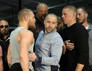 Conor McGregor (L) and Nate Diaz (R) are held apart by UFC PR vice president Dave Sholler (C). (Getty)