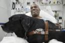 Cecil Williams smiles as he pets his guide dog Orlando in his hospital bed following a fall onto subway tracks from the platform at 145th Street, Tuesday, Dec. 17, 2013, in New York. The blind 61-year-old Williams says he fainted while holding onto his black labrador who tried to save him from falling. Both escaped without serious injury. (AP Photo/John Minchillo)