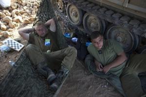 Israeli soldiers rest next to an APC outside the Gaza &hellip;