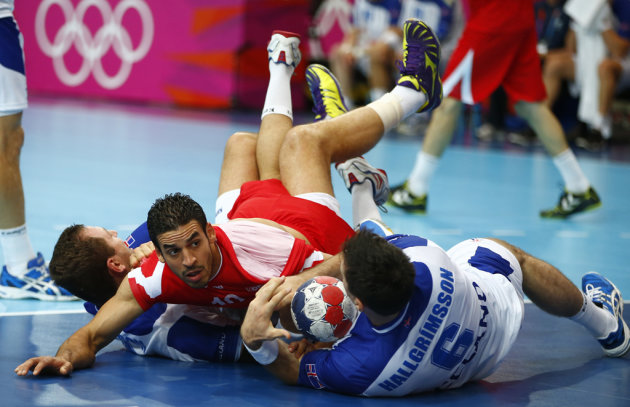 Tunisia's Kamel Alouini falls to the ground after colliding with Iceland's Sverre Jakobsson and Asgeir Orn Hallgrimsson in their men's handball Preliminaries Group A match at the Copper Box venue duri