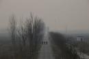 FILE PHOTO: People walk along a village road on a polluted day on the outskirts of Langfang