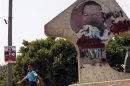 Egyptian boy walks near defaced picture of former Egyptian President Mubarak and poster of presidential candidate Fotouh in Cairo