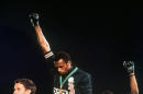 FILe - In this Oct. 16, 1968, file photo, U.S. athletes Tommie Smith, center, and John Carlos stare downward while extending gloved hands skyward during the playing of the Star Spangled Banner after Smith received the gold and Carlos the bronze for the 200 meter run at the Summer Olympic Games in Mexico City. Australian silver medalist Peter Norman is at left. Smith and Carlos, the American sprinters whose raised-fist salutes at the 1968 Olympics are an ageless sign of race-inspired protest, will join the U.S. Olympic team at the White House next week for its meeting with President Barack Obama. Smith and Carlos were sent home from the Olympics after raising their black-gloved fists in a symbolic protest during the U.S. national anthem. They called it a ``human rights salute.'' The USOC asked them to serve as ambassadors as it tries to make its own leadership more diverse. (AP Photo/File)