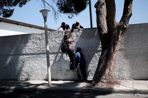 Migrants climb over a wall at the stadium where they&nbsp;&hellip;