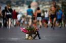 People walk near a bouquet of flowers placed in tribute to victims of the truck attack along the Promenade des Anglais on Bastille Day killing scores and injuring as many in Nice