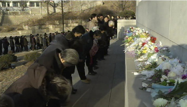 In this image made from Associated Press Television News, North Koreans gather to mourn the death of North Korean leader Kim Jong Il in front of a mural depicting Kim Jong Il and his father Kim Sung I