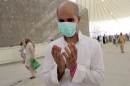 A Muslim pilgrim wearing a medical mask prays
