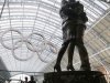 A couple pauses at the foot of a statue with the Olympic rings hung in the rafters of St. Pancras Station prior to the 2012 Summer Olympics, Tuesday, July 24, 2012, in London. The opening ceremonies for the 2012 London Olympics will be held Friday, July 27. (AP Photo/Charles Krupa)