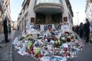 People lay flowers and candles at the offices of the satirical magazine Charlie Hebdo in Paris which was attacked by armed French nationals Cherif and Said Kouachi on January 11, 2015