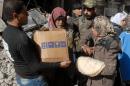A handout picture released by the official Syrian Arab News Agency (SANA) on January 30, 2014 shows residents of Syria's besieged Yarmuk Palestinian refugee camp, south of Damascus, receiving food from the UN Palestinian refugee agency (UNRWA)