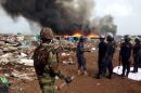 Security forces watch as residents burn dwellings in an impoverished neighborhood in Accra